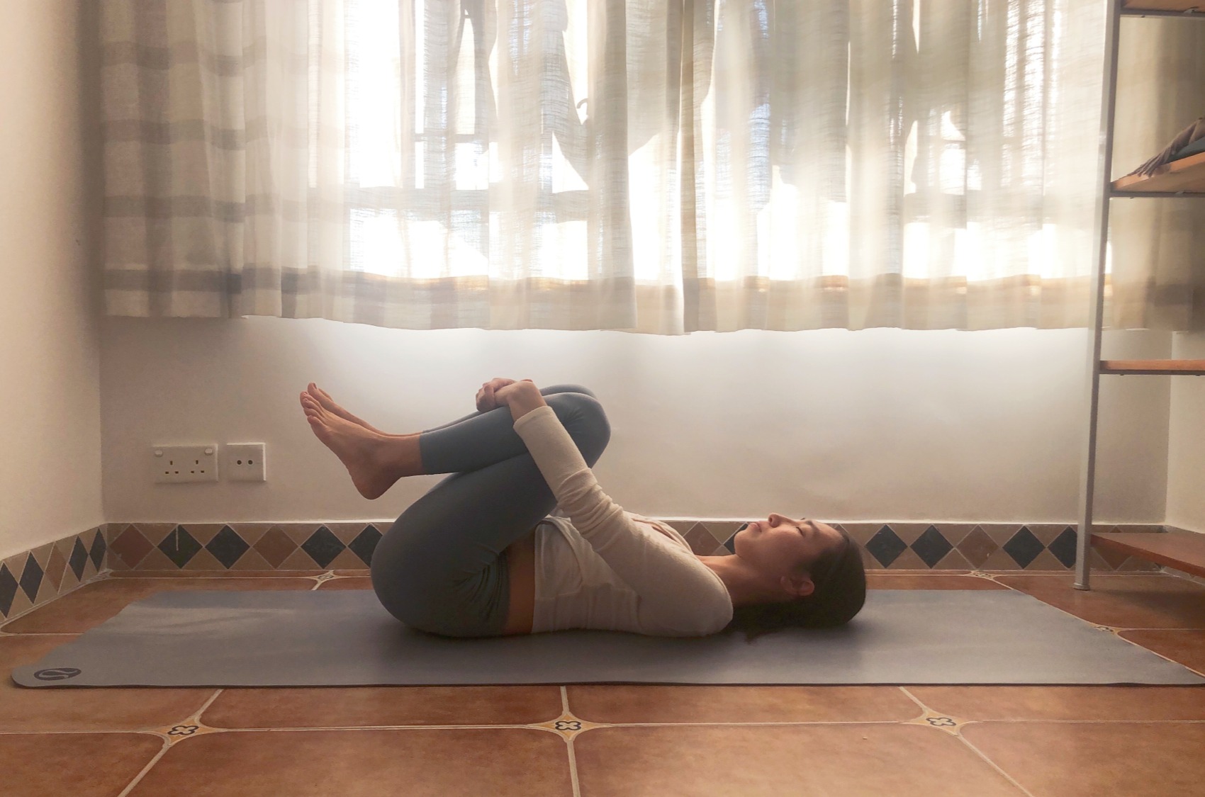 Full Wind Pose with knees hugged towards the chest